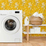 Transform any space into an autumnal paradise with this stunning floral wallpaper that combines gentle white blossoms with an intense mustard yellow background. The small-scale botanical illustrations in this design are simple and almost motif-like, balancing the dramatic yellow hue with a mild whimsical vibe.&nbsp;Try this PVC-free wallpaper to completely transform your bathrooms and utility spaces.